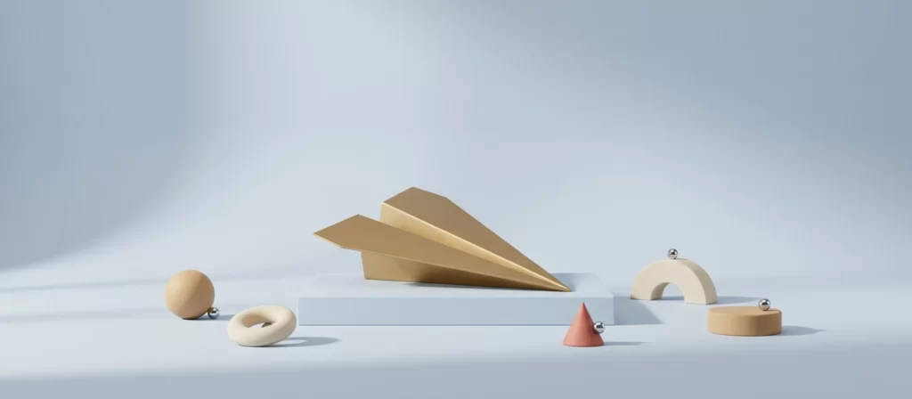 Avión de papel de latón mate sobre un pedestal bajo, entre formas geométricas de arcilla