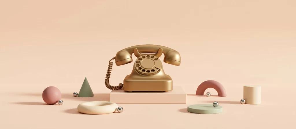 Teléfono antiguo de disco, de latón, sobre un pedestal bajo, entre formas geométricas de arcilla